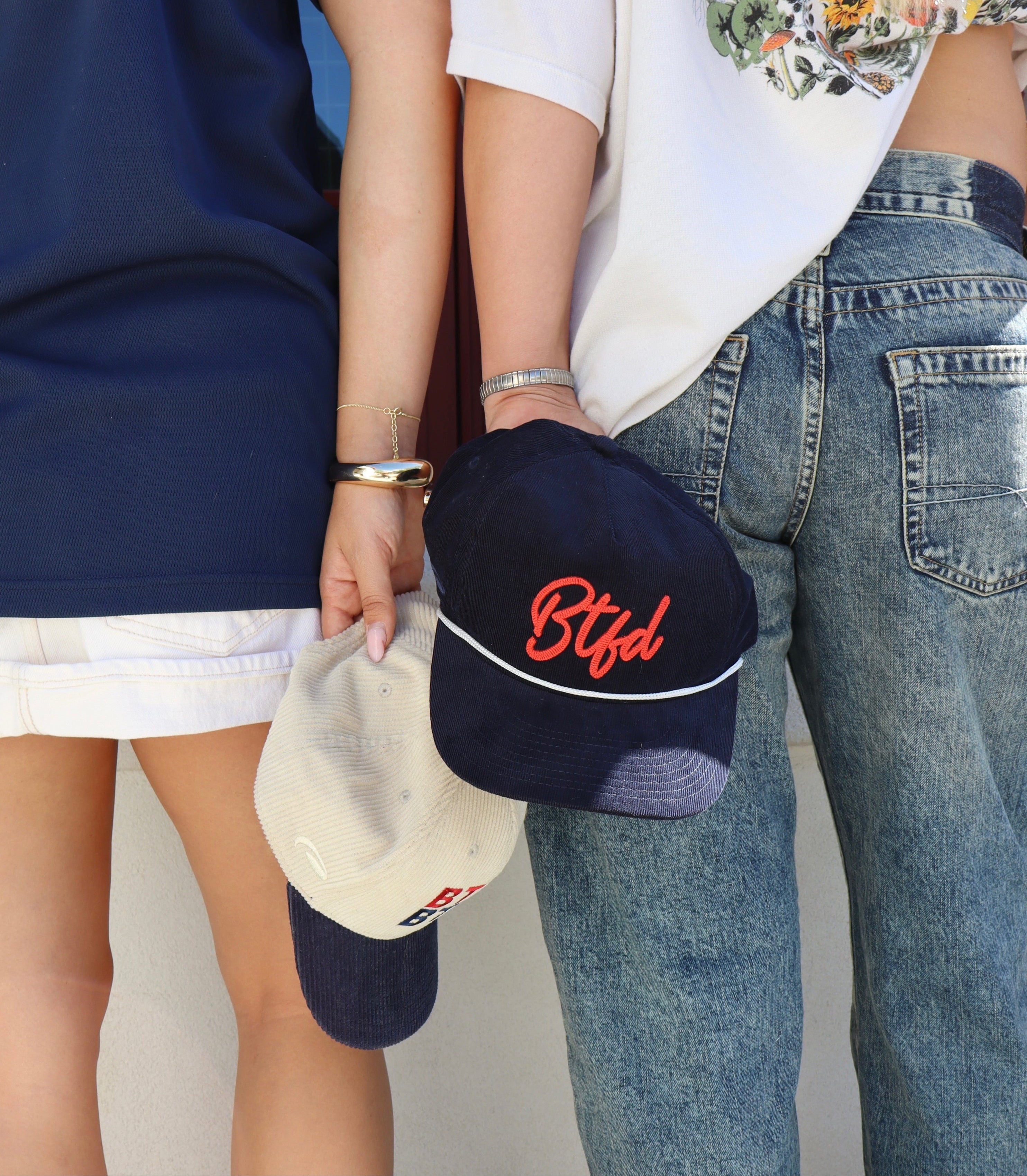 navy corduroy hat with script 'BTFD' held by a girl