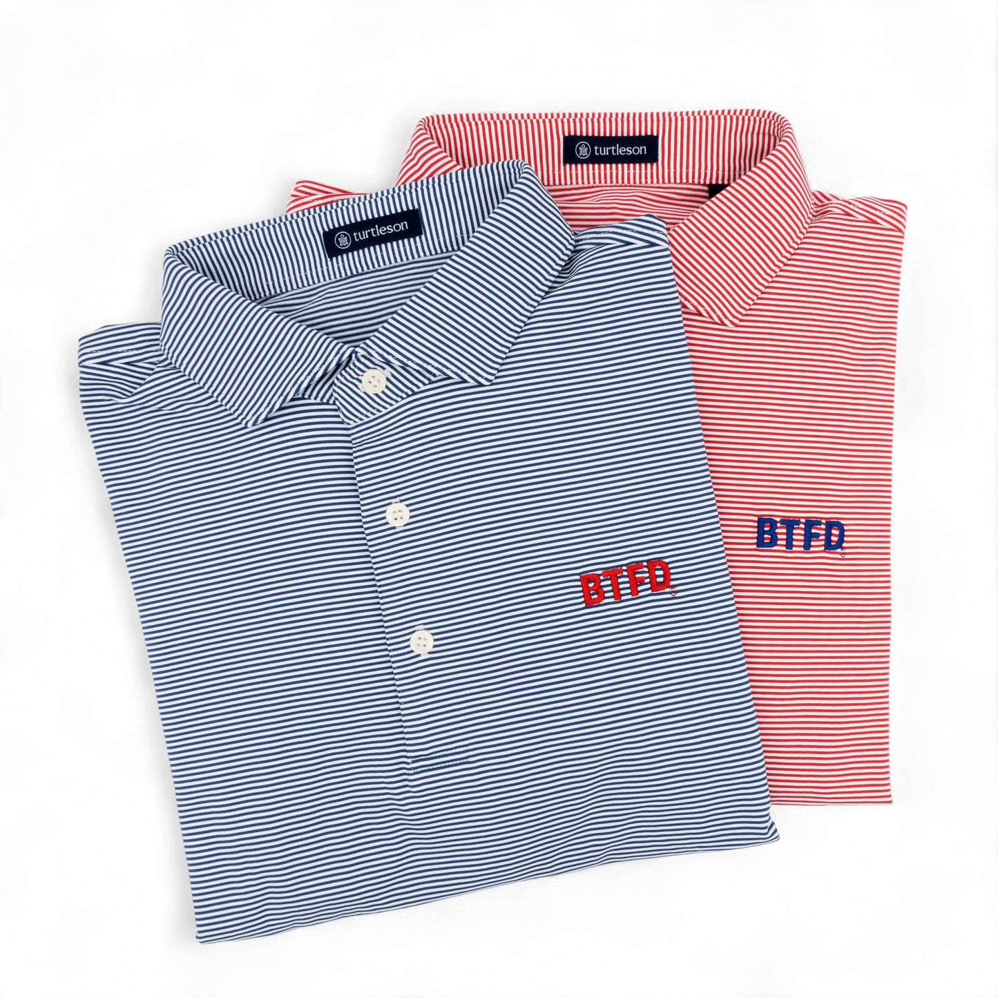 Two folded golf shirts, one blue and one red, with embroidered 'BTFD' text on a white background.