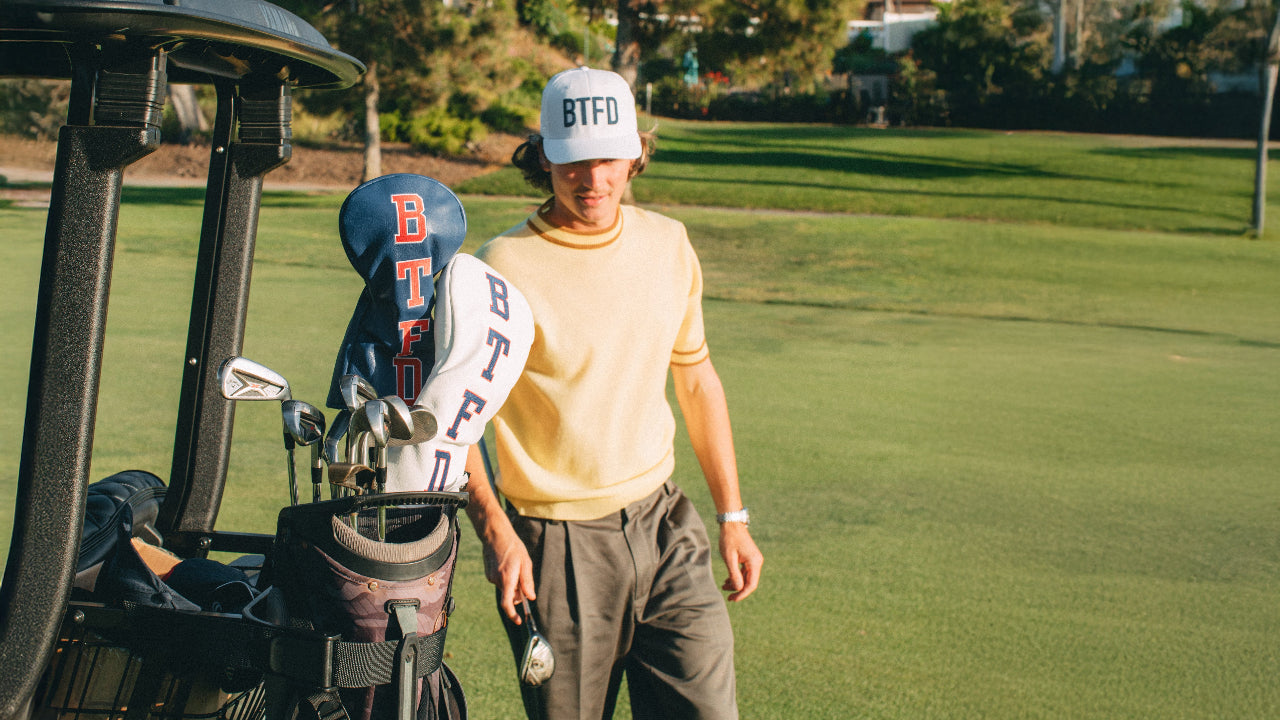 White hat with embroidered 'BTFD' in navy. BTFD golf club covers in golf bag. 